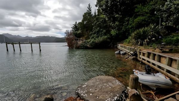 In this image, our dinghy is tied to the dinghy dock, it is high tide so the water is reaching the dinghy dock, and you can see the tidal frame in the shallow waters where boats can tie alongside and do some boat maintenance.