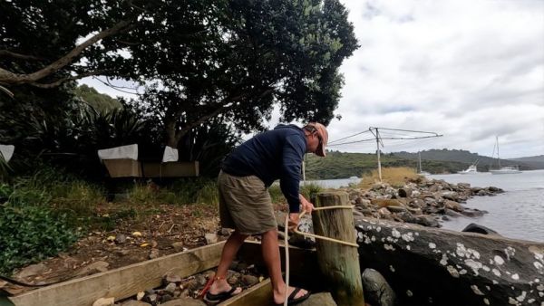 In this image, Adam is tying up the dinghy to the dinghy docks to secure it. It is high tide so the dinghy is floating.